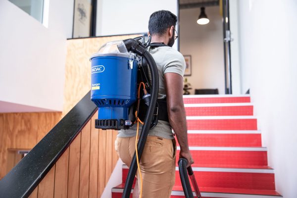 man walking up stairs with a pacvac vacuum cleaner