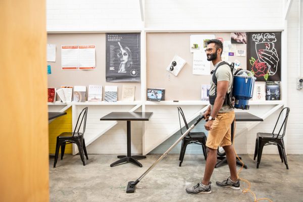 man wearing a pacvac Superpro vacuum cleaner, cleaning a school