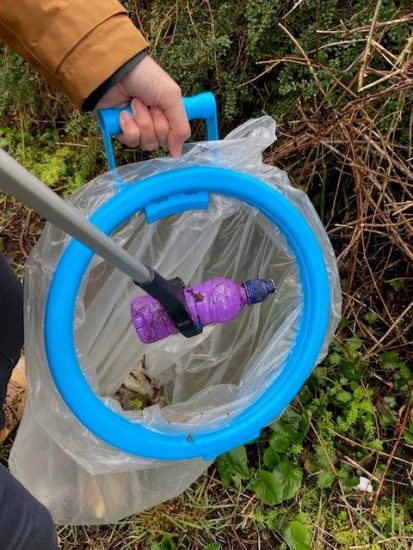 a plastic bottle being picked up with a litter picker