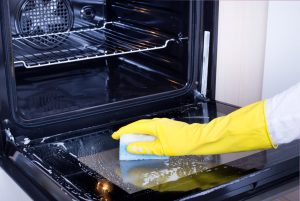 OVEN CLEANING WITH RUBBER GLOVES AND SPONGE